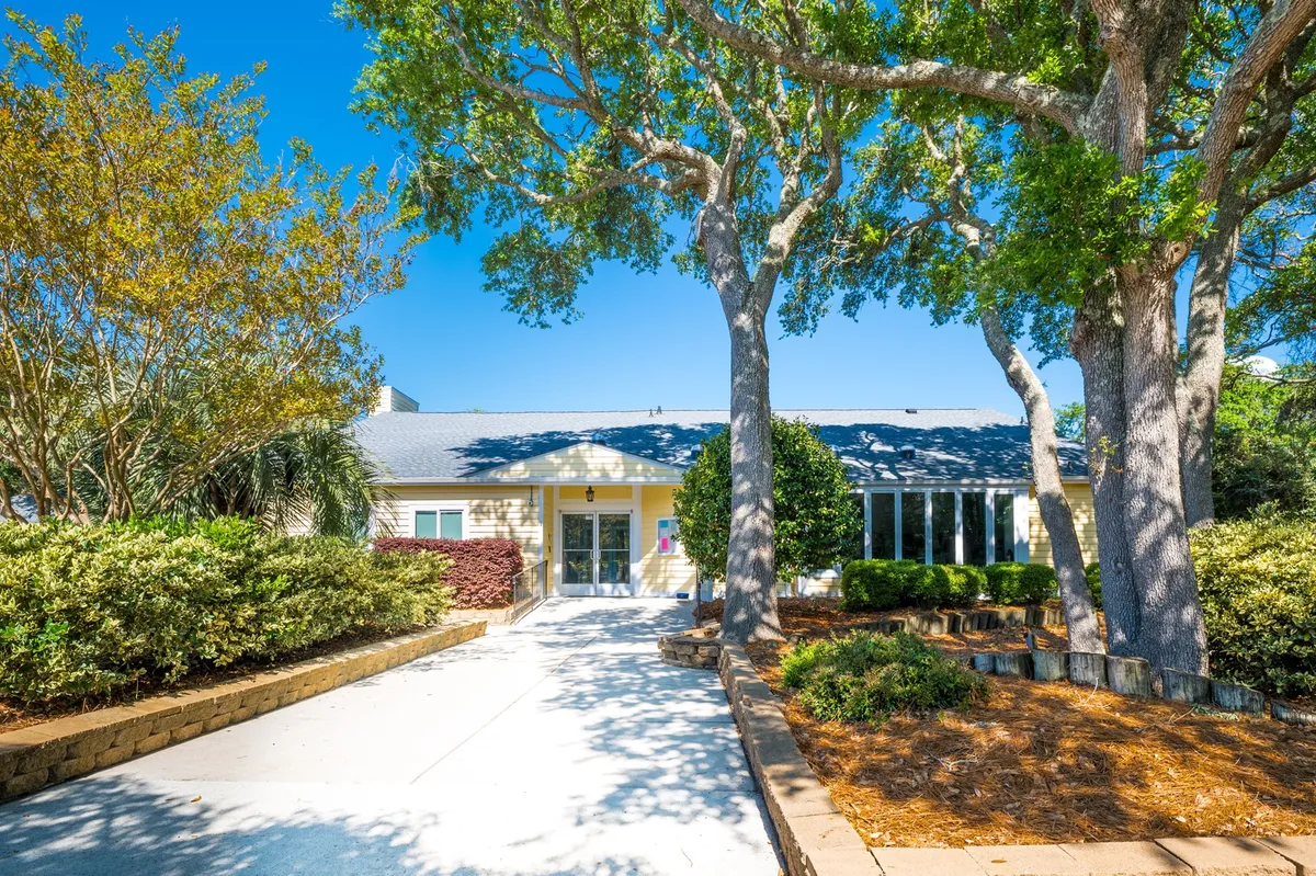 An exterior shot highlighting the resort’s entrance, shaded by large trees and framed by a neatly landscaped garden. The inviting path and greenery evoke a sense of arrival and anticipation for the experiences nearby.