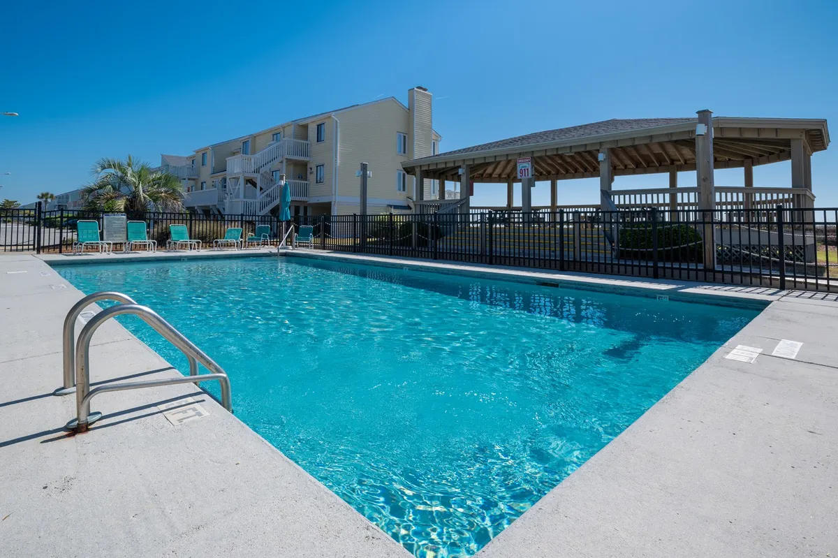 An inviting exterior view of the pool area featuring a charming gazebo, poolside lounge chairs, and lush landscaping. The atmosphere is set for both relaxation and lively poolside gatherings, with sunset hues enhancing the mood.