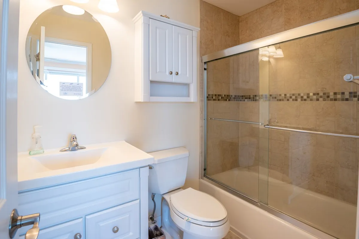 A fresh, inviting bathroom with a circular mirrored vanity, white cabinetry, and a glass shower enclosure. The space feels modern and spa-like, perfect for refreshing routines or unwinding after a long day.